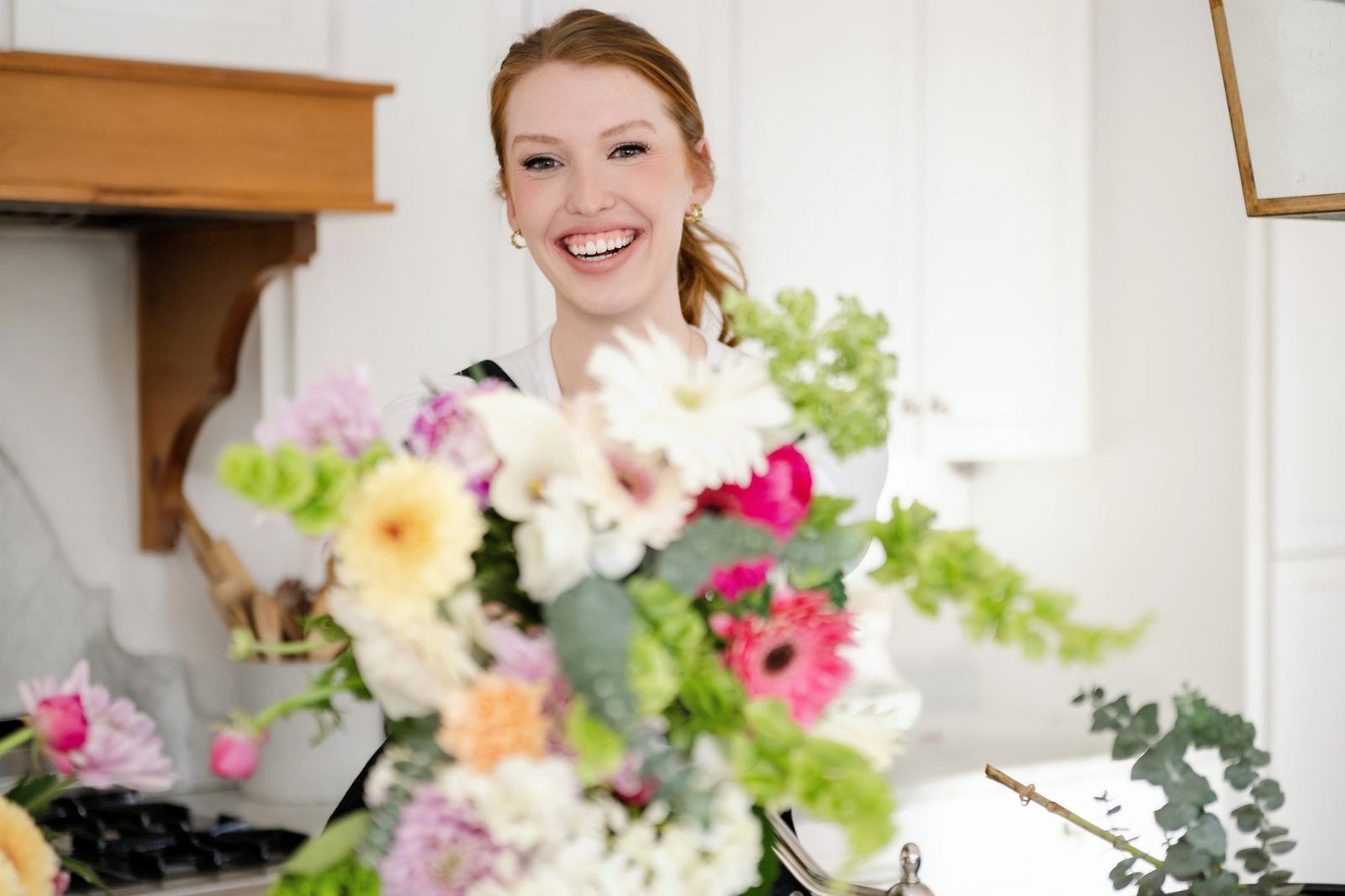 Megan holding a mixed bouquet in the kitchen