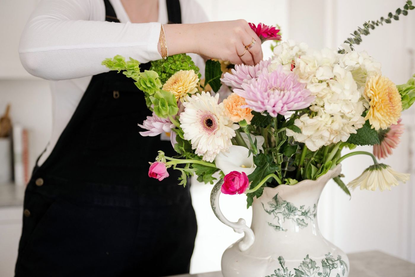 Megan arranging flowers in a blue and white vase